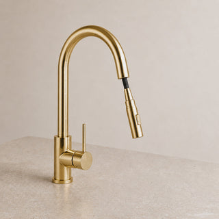 Gold kitchen tap on a beige countertop with a neutral background