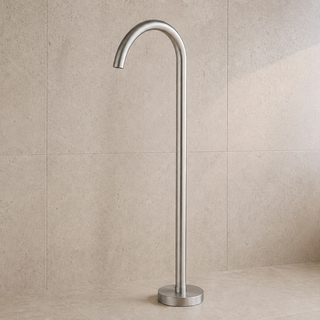 Stainless steel nickel freestanding gooseneck bathtub tap against a beige tiled wall.