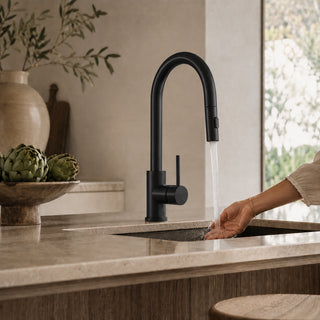 Person washing hands under a black kitchen tap in a modern organic kitchen.