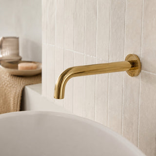 polished gold bathroom wall tap in a modern bathroom with a free standing bath